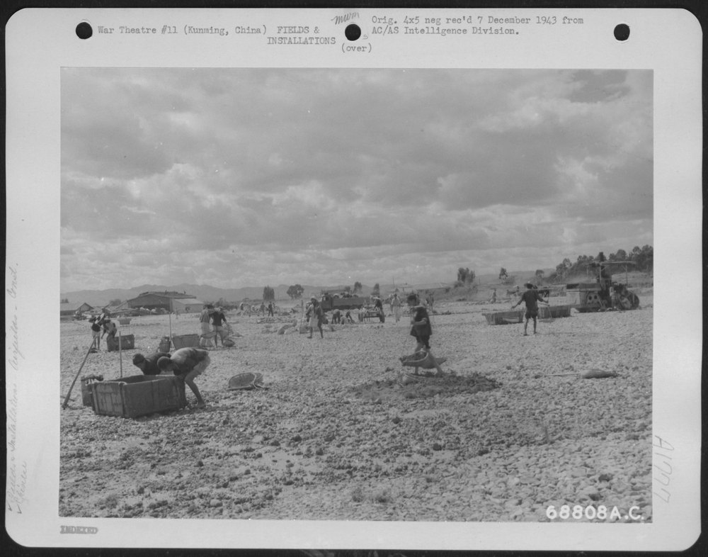 Chinese laborers spread crushed rock on the field of the India China