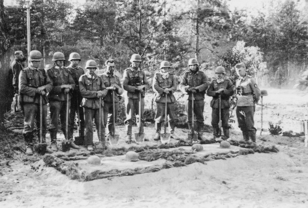German soldiers stand with shovels at the grave of the commanding officer. They are with a reconnaissance unit in the woods of Dzuskawcza, Soviet Union during operation Barbarossa