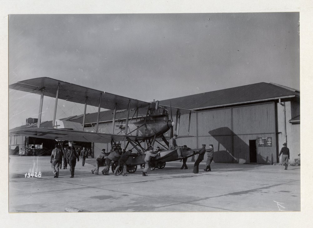 Ground crew moving a floatplane on its beaching trolley outside the hangar, Helgoland