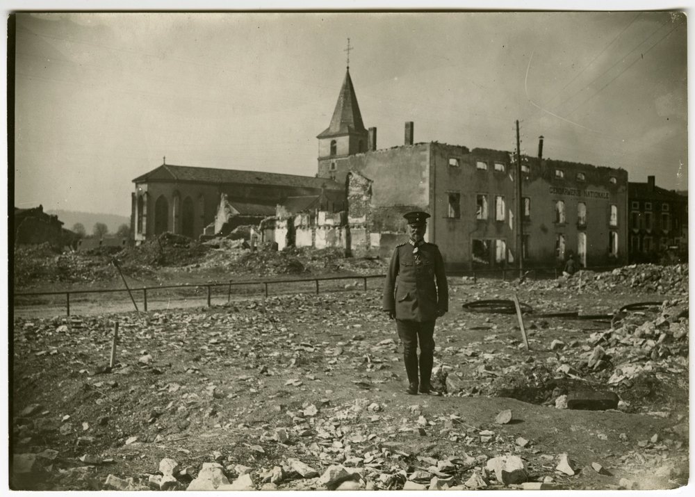 Man in military uniform amidst war-damaged buildings