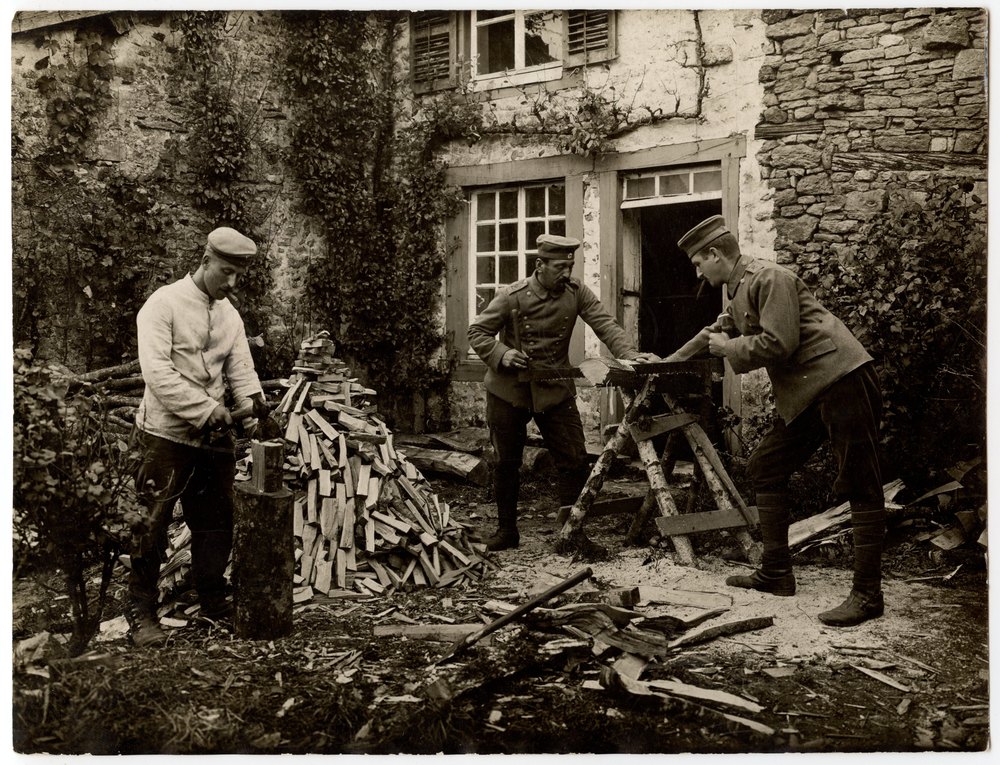 Men chopping and sawing wood in a yard