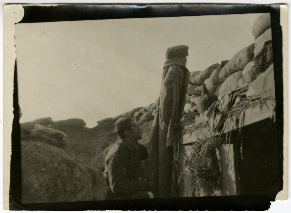Men in a trench with sandbags and straw