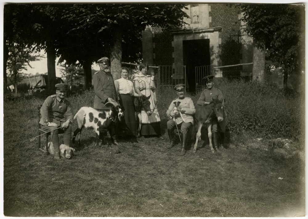 Military men with women and animals in a grassy field