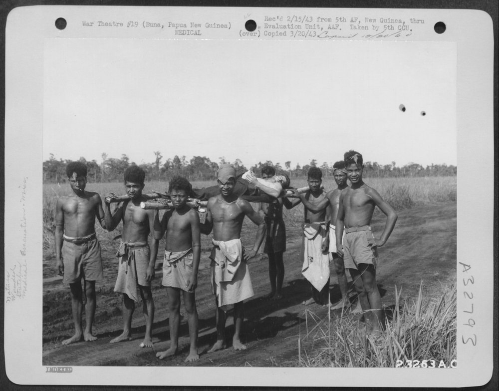Natives with wounded troops at Buna