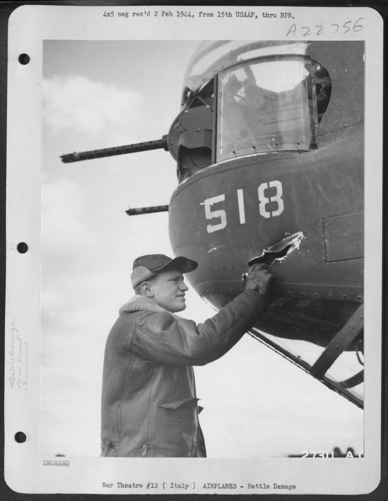 Sgt Hahn examines shell hole in B-24