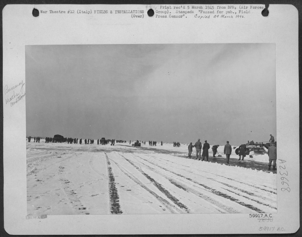 The engineers go to work on the snow-covered runway of an Allied