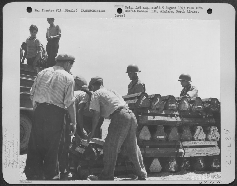 Under the supervision of American soldiers, Sicilian civilians unload